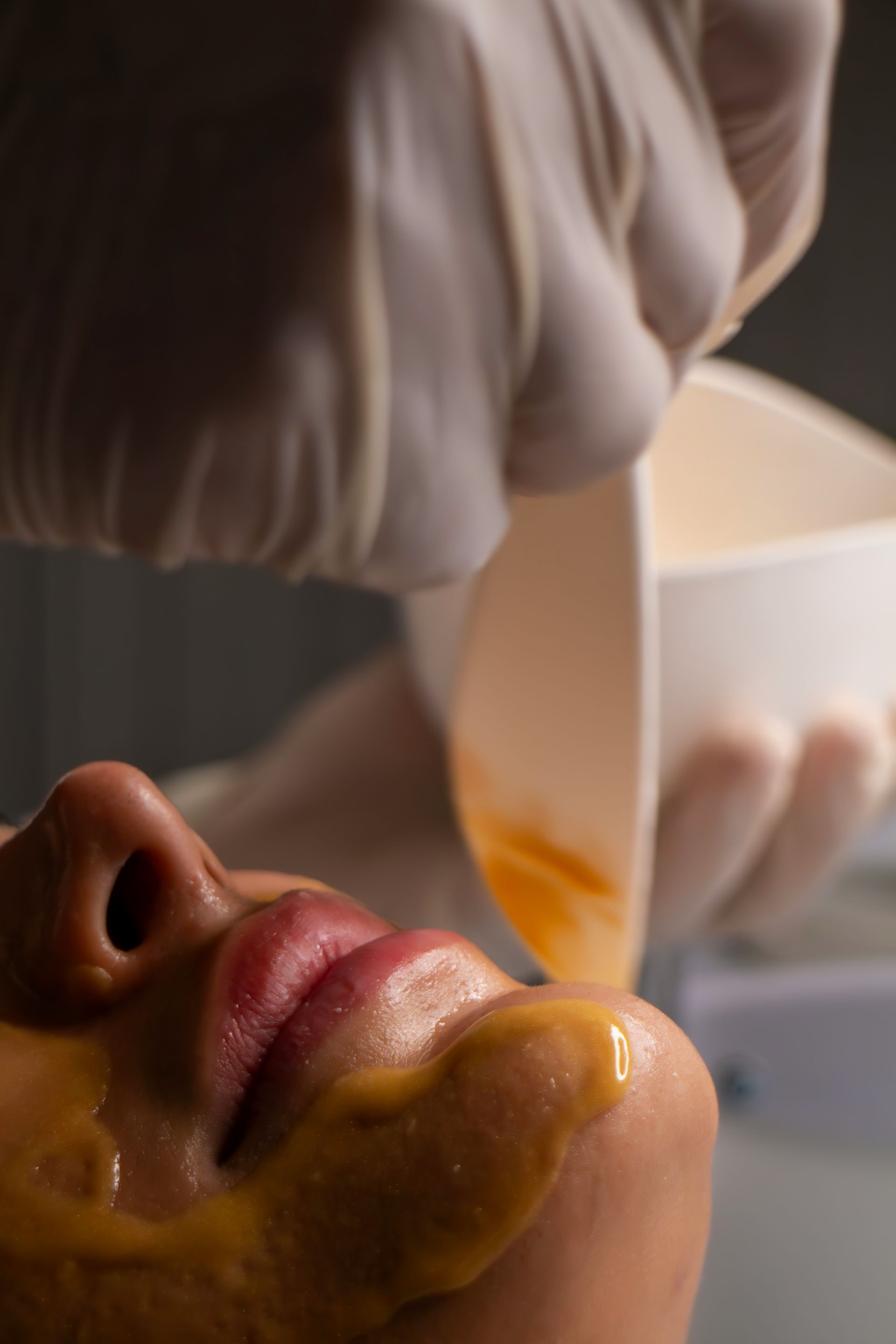 Beautician applying facial mask to woman's face